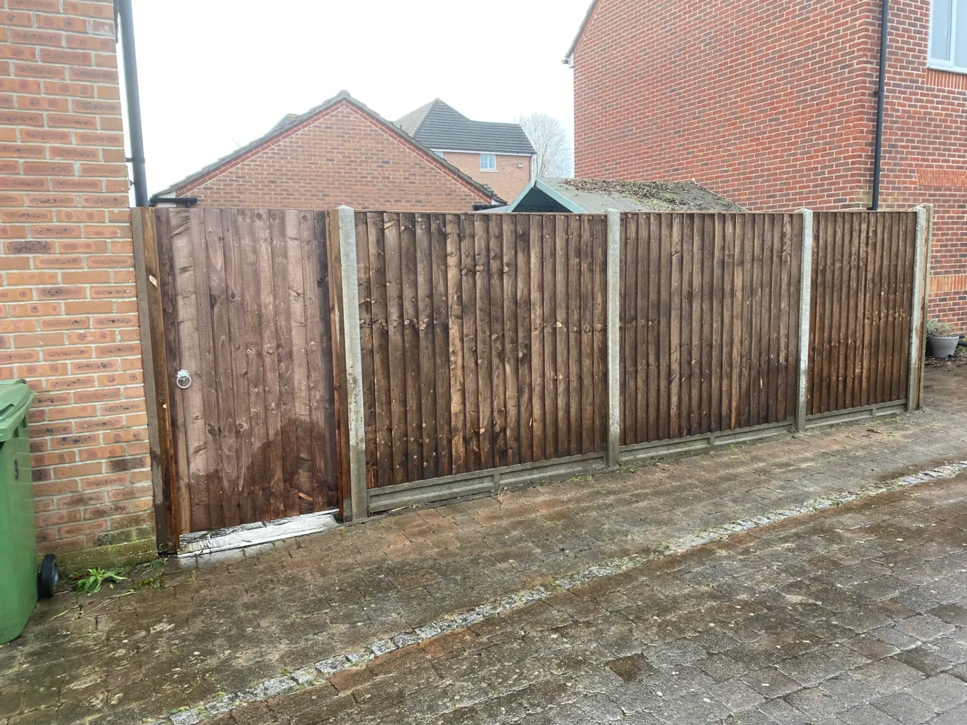 Fence panels and matching side gate installed on a paved driveway in Surrey