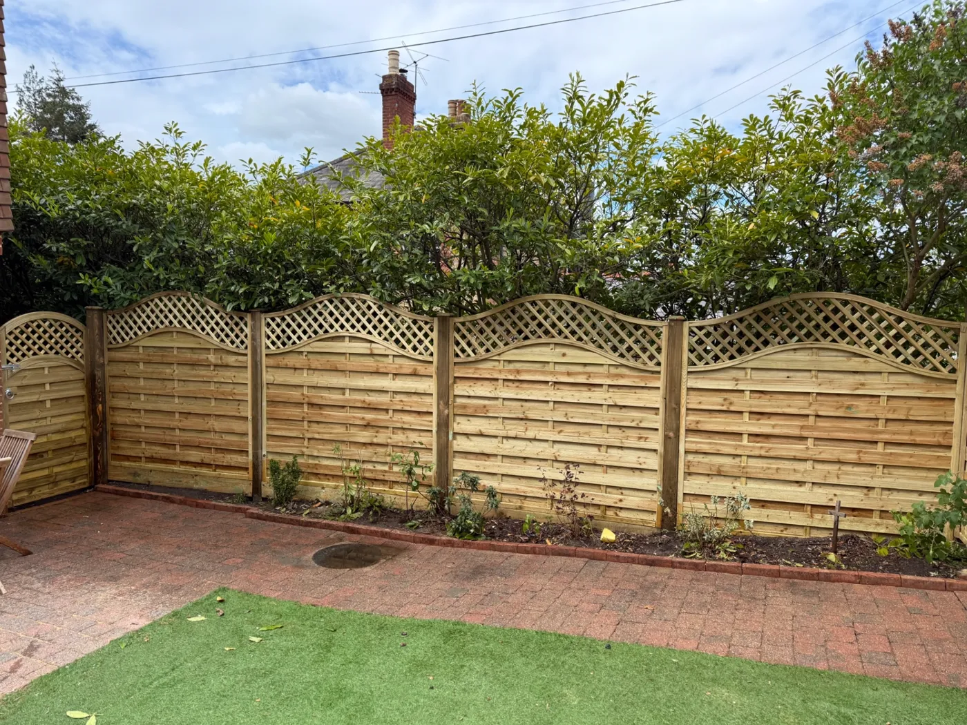 Wavy trellis topped garden fence panels fitted along a Surrey patio